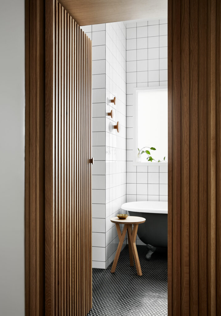 Maike Design bathroom with clawfoot bath and concealed timber door