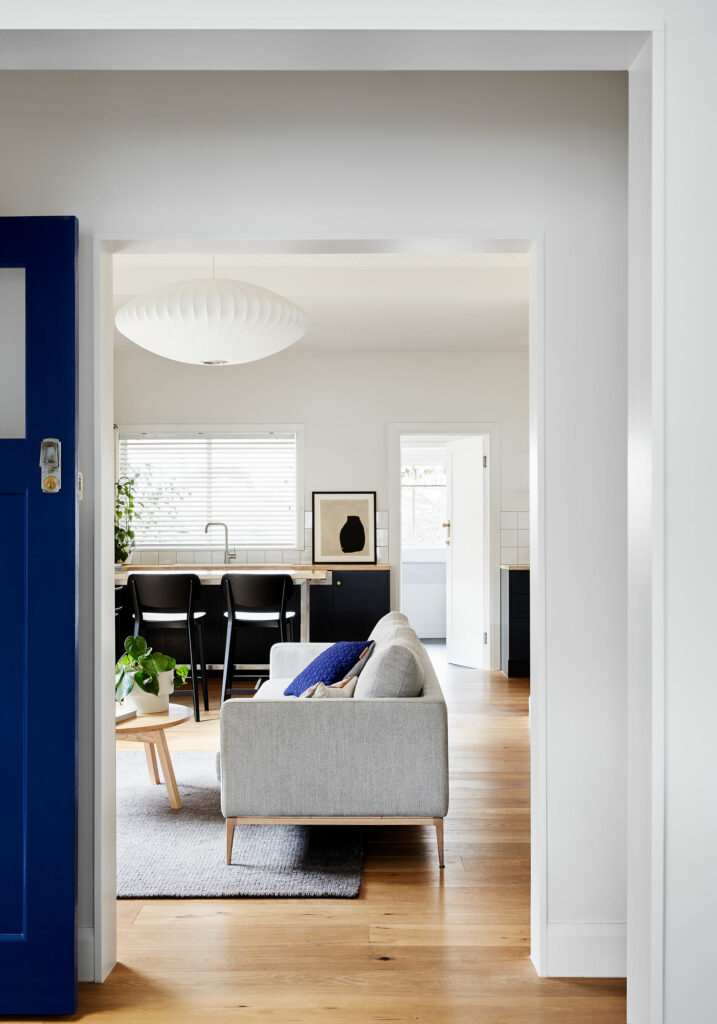 Maike Design lounge and kitchen. Grey couch and timber floors