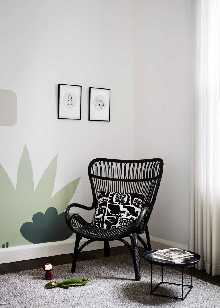 Maike Design nursery with artwork, wicker chair and hand painted mural