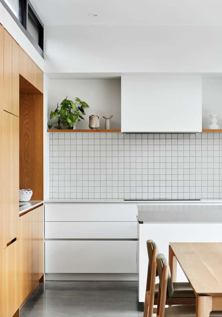 Maike Design kitchen. Timber joinery, white joinery with stone tops. Textured tile splashback. Timber dining table