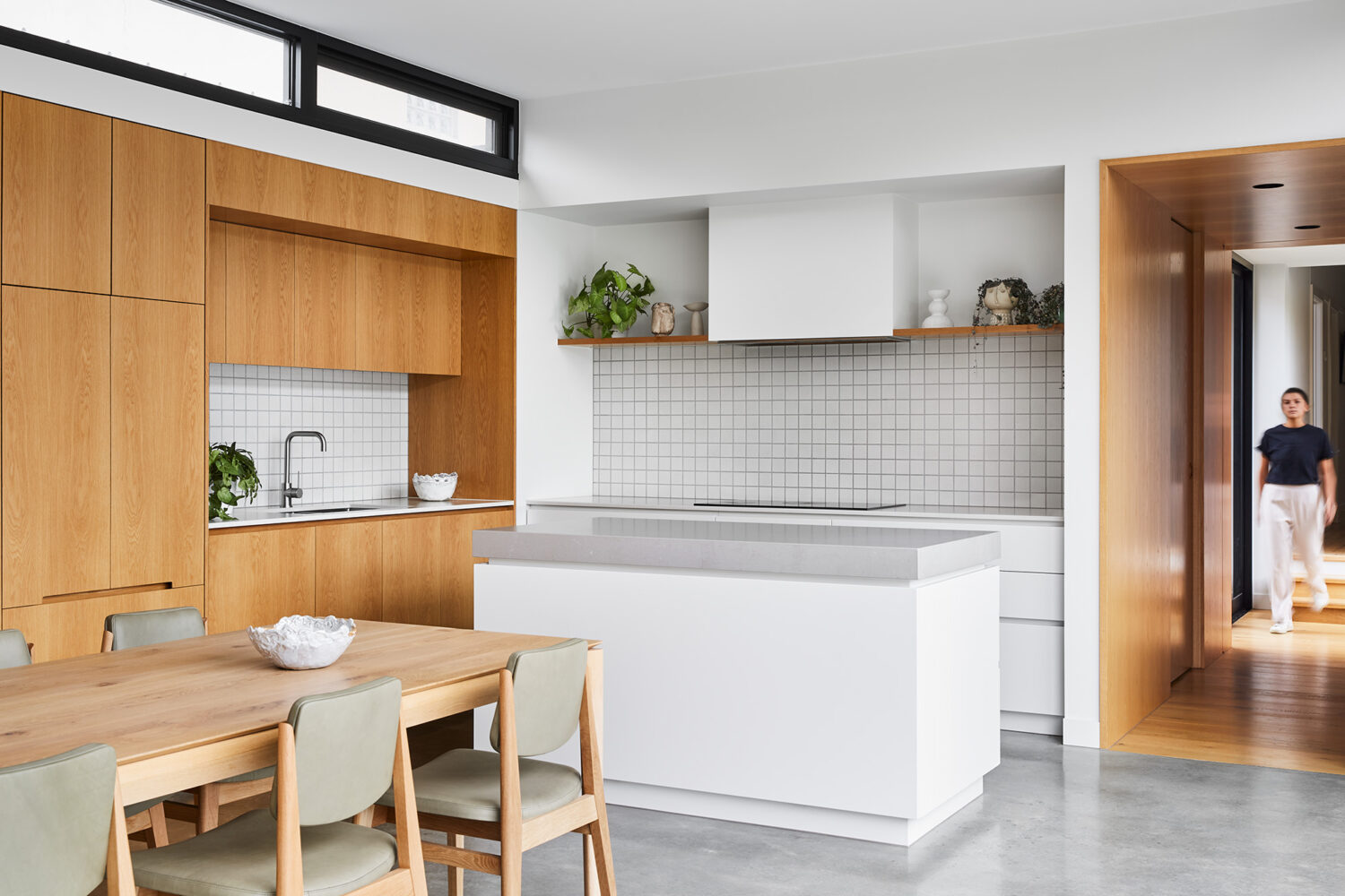 Maike Design kitchen. Timber joinery, white joinery with stone tops. Textured tile splashback. Timber and glass hallway link